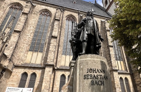 A photo of a statue of Johann Sebastian Bach in front of a brick building.